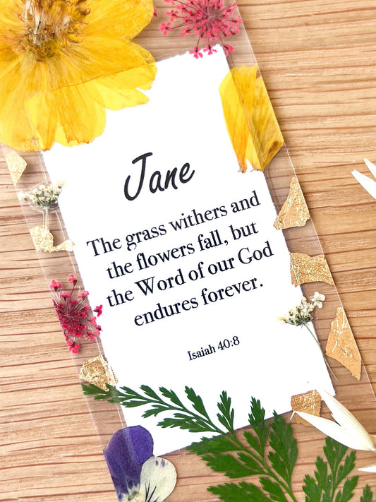  Bookmark includes the following scripture passage : "[custom name] The grass withers and the flowers fall, but the Word of our God endures forever. Isaiah 40:8"