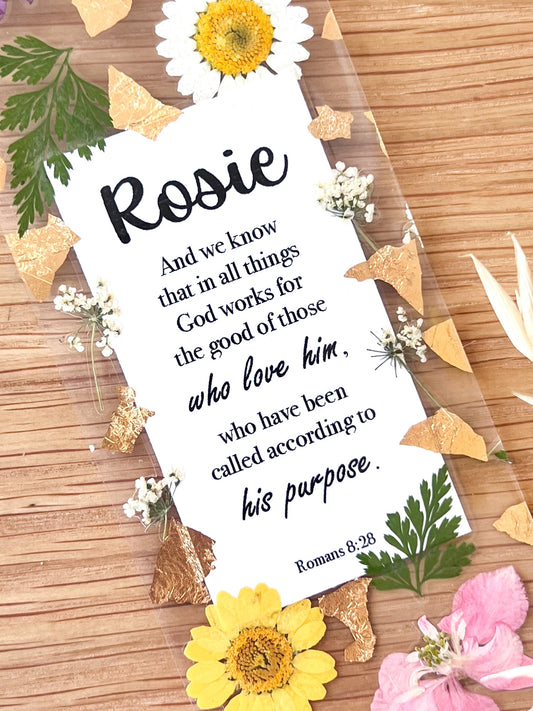 Bookmark includes the following scripture passage : "[custom name] And we know that in all things God works for the good of those who love him, who have been called according to his purpose. Romans 8:28"